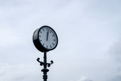 Low angle view of clock against sky