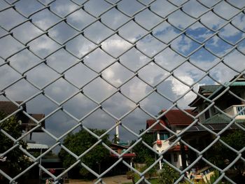 Close-up of chainlink fence against cityscape