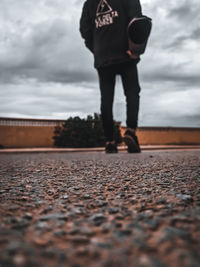 Low section of man standing on pebbles in city