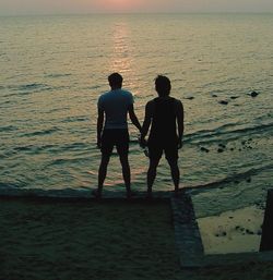 People standing on beach at sunset