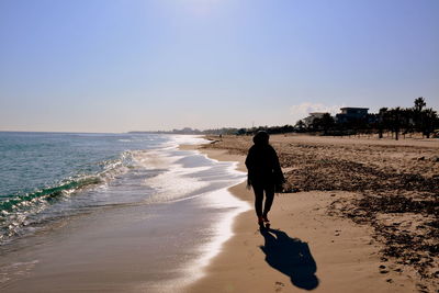 Rear view of woman walking on beach