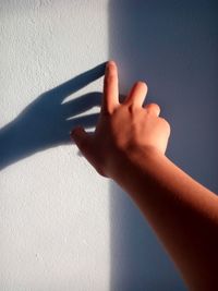 Cropped hand of woman touching white wall