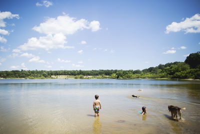 People and dog on lake against sky