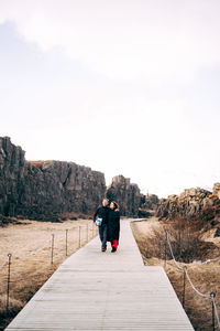 Rear view of woman on footpath against sky