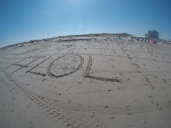 Text on sand at beach against clear blue sky