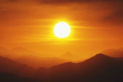 Scenic view of silhouette mountains against romantic sky at sunset