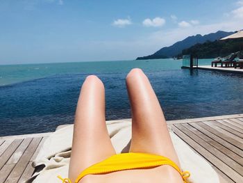 Low section of man lying on beach against sky