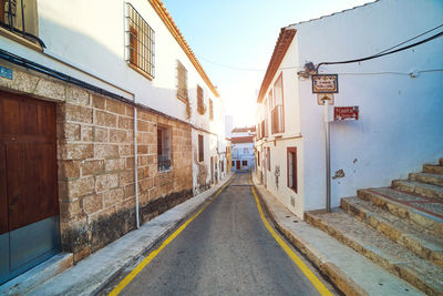 Empty road amidst buildings against sky