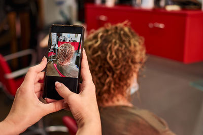 Hairdresser takes a picture of her work after cutting a client's hair