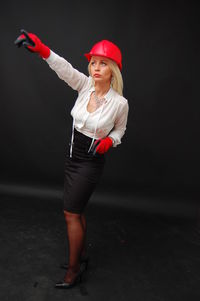 Full length of young woman standing against black background