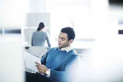 Serious businessman reading document while sitting in office