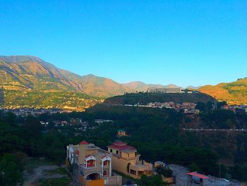 Houses on mountain range against clear blue sky