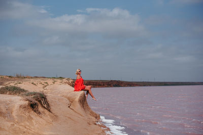 Rear view of woman standing at beach against sky