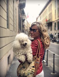 Smiling woman with dog walking in city