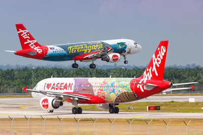 Red airplane flying over airport runway against sky