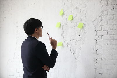 Side view of boy standing against white wall