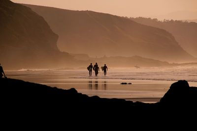 Silhouette surfers on beach