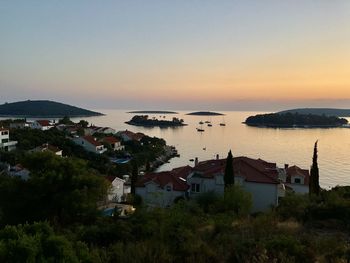 High angle view of sea and buildings against sky at sunset