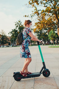 Young woman riding an electric scooter in the city center. woman wearing the face mask