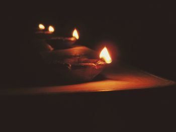 Close-up of hand holding lit candles in darkroom