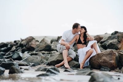 Young couple on rock against sky