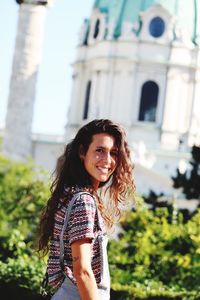 Portrait of smiling young woman standing against building