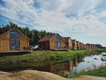 Houses by lake and buildings against sky