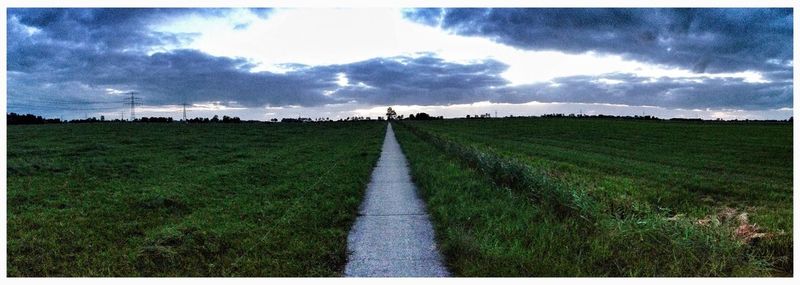 Scenic view of grassy field against cloudy sky