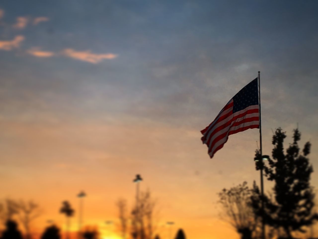 LOW ANGLE VIEW OF FLAGS AGAINST SKY DURING SUNSET