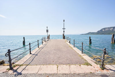 Rear view of man walking on pier over sea against sky