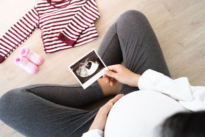 Pregnant woman holding a fetal ultrasound image by baby cloth