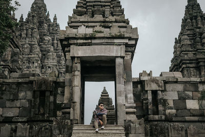 Low angle view of man sitting on staircase of temple