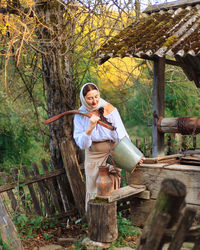 Portrait of young woman standing against tree trunk