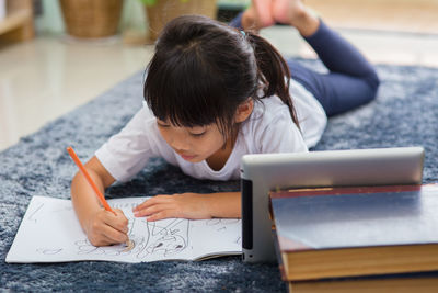 Rear view of girl looking at book on table