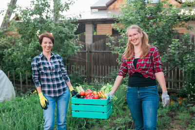 Portrait of smiling young woman holding vegetables at park