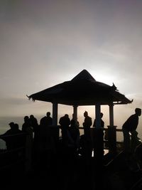 Silhouette people sitting against sky during sunset