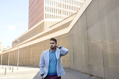 Man looking away while standing against modern building