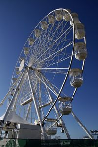 Low angle view of ferris wheel against blue sky