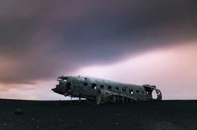 Abandoned vehicle on land against sky during sunset