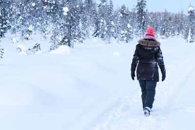 Rear view of woman skiing on snow covered field