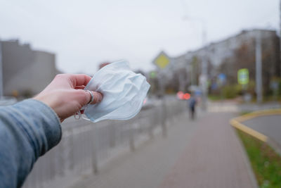 A man's hand holds a medical mask in his hand, in the city, an accessory with him, as a safety from