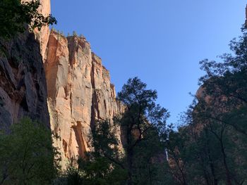 Low angle view of rocks against clear blue sky