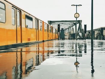 Reflection of train and clock on wet railroad station platform during monsoon