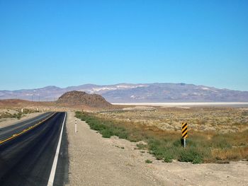 Road by desert against clear blue sky