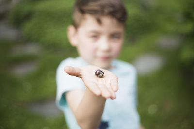 Boy showing snail on palm in back yard