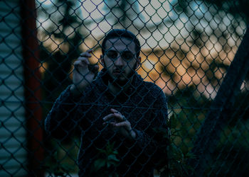 Portrait of man seen through chainlink fence