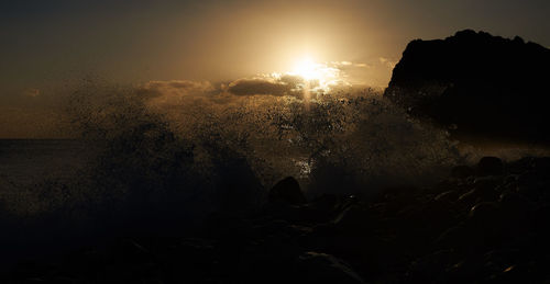 Scenic view of silhouette rocks against sky during sunset