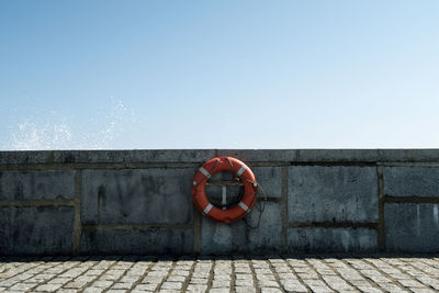 Inflatable ring hanging on retaining wall against clear sky