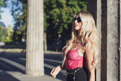 Woman wearing sunglasses standing against column