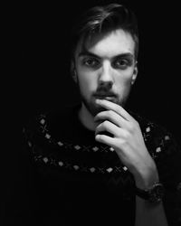 Portrait of young man against black background